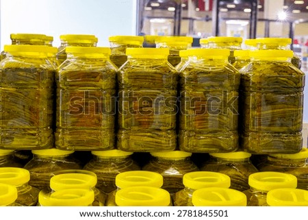 Stack of preserved grape leaves for dolma, glossy texture in a tight frame; for food design, packaging, retail promotion, recipe content. canned grape leaves, for cooking dolma, on a plate,Canned grape leaves, for cooking dolma, on a plate. Jars of various pickled vegetables. Canned grape leaves.