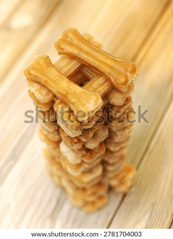 Stack of rawhide dog bones arranged in a tower shape on a wooden background.