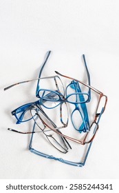 A stack of reading glasses with plastic and metal frames isolated on a white background
