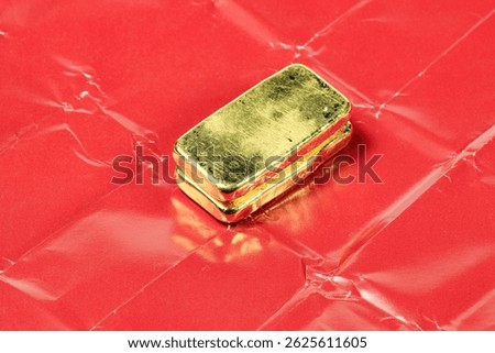 A stack of real shiny gold bars or gold ingots On the red paper used to wrap gold when trading retail in Asia.