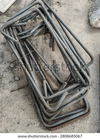 A stack of rectangular steel rebar stirrups on the ground, ready for concrete column reinforcement at a construction site