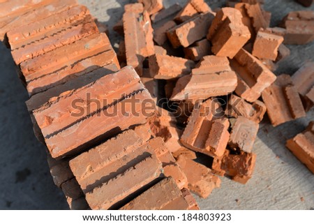 A stack of red clay bricks and broken bricks on the floor in constuction site