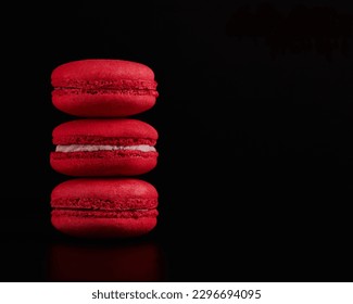Stack of red macarons on a black background. Copy space to insert text or design, selective focus, low key