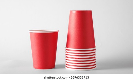 Stack of red paper cups on white background for beverage packaging and branding. Concept of disposable cup design, cafe mockup, product presentation for restaurant and catering ads.