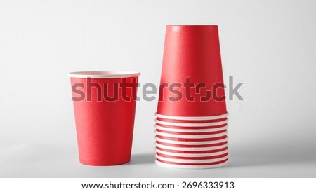 Stack of red paper cups on white background for beverage packaging and branding. Concept of disposable cup design, cafe mockup, product presentation for restaurant and catering ads.