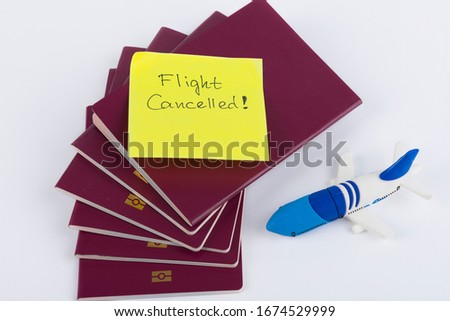 A stack of red passports, Note Flight Cancelled and small airplane toy isolated on White Background . Travel concept