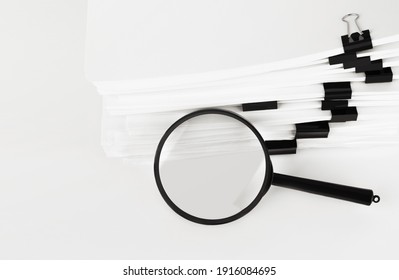 Stack of report paper documents with magnifying glass. Concept of business and search