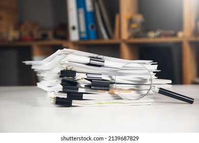 Stack of report paper documents with magnifying glass. Concept of business and search.