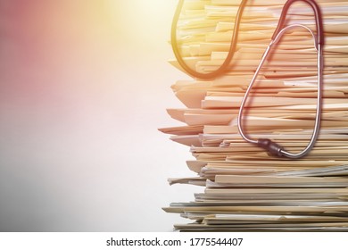 Stack of report paper documents and stethoscope