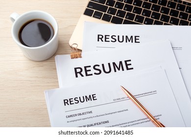 Stack Of Resumes On Laptop With Pen And Coffee Cup On Wood Desk, Resume Review, Job Interview