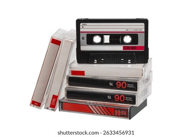 Stack of retro audio cassette tapes with one positioned upright, isolated on white background.