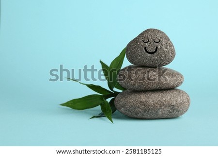Stack of rocks with drawn smiley face on light blue background, space for text. Harmony and life balance