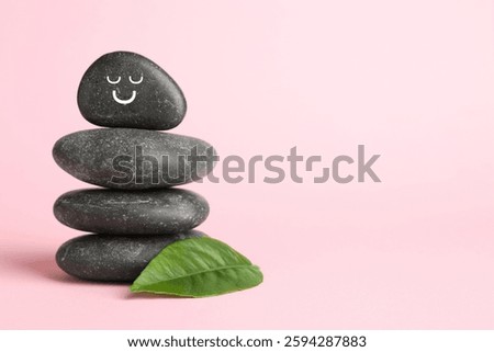 Stack of rocks with drawn smiley face on light pink background, space for text. Harmony and life balance