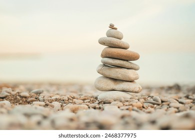 A stack of rocks on a beach. The rocks are of different sizes and are piled on top of each other. The scene is peaceful and serene, with the ocean in the background
