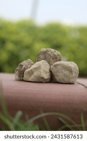 Stack of rocks on brick sidewalk. Pile of stones on red bricks. Rocks arranged on urban walkway. Stones on brick pathway. 