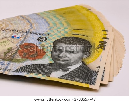 A stack of Romanian 200 lei banknotes featuring Lucian Blaga. The bills are fanned out against a plain white background, highlighting their vibrant yellow and green colors and security features.
