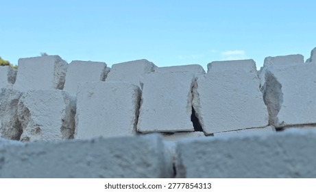 A stack of rough, white, broken concrete blocks against a clear blue sky.