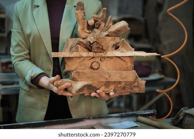 A stack of rough-hewn wood slabs is held in a craftsperson's hands, each piece rich with unique textures and the promise of future projects.