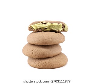 Stack of round cocoa cookies filled with pistachio cream on white background.