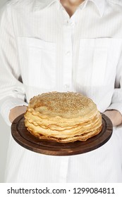 Stack of russian pancake blini in rustic wooden dish woman holds in hands. Close-up with copy space