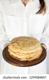 Stack of russian pancake blini in rustic wooden dish woman holds in hands. Close-up with copy space