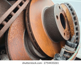 stack of rusty brake discs and car parts, closeup of used automotive brake rotors with corrosion texture, mechanical spare parts in repair workshop