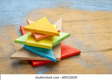stack of seven colorful tangram wooden pieces, a traditional Chinese puzzle game on a grunge wooden background
