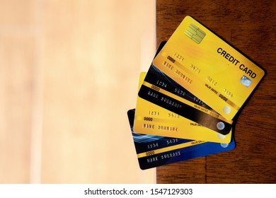 A stack of several colored credit cards closely on the wooden table and yellow floor.