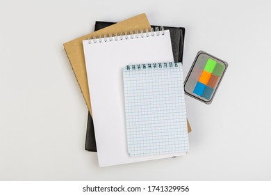a stack of several spiral school notebooks lies on a white table with a pencil, office concept