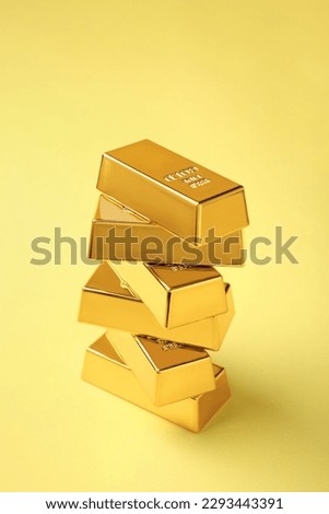 Stack of shiny gold bars on yellow background