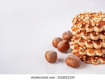 a stack of shortbread cookies with nuts and hazelnuts on a white glass, close-up, copy space