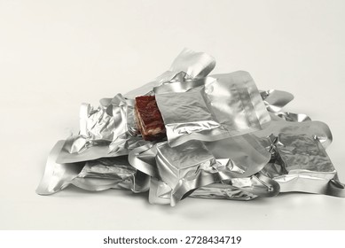 Stack of silver foil-wrapped snack packages with one unwrapped date nut pie bar visible, showing fresh delicious convenient vegan snacks ready to eat.