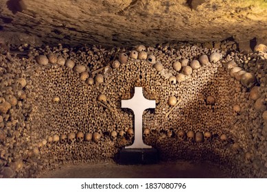 Stack of skulls and bones with a white cross in the catacombs of Paris, France