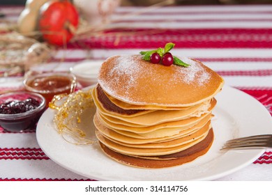 Stack of Small pancakes with fresh berries and  mint served with set of sauces in the national style on the white plate closeup