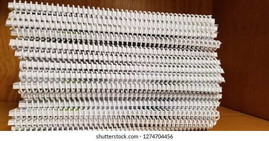 Stack of small spiral bound textbooks on bookshelf side edge view
