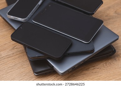 Stack smartphones, tablets, and laptops on a wooden table, showcasing modern digital devices. Concept technology abundance, multitasking, gadget collection and contemporary digital lifestyle