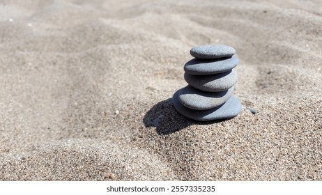 A stack of smooth stones balanced precariously on a sandy beach, creating a sense of tranquility and harmony. - Powered by Shutterstock