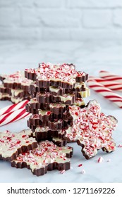 Stack of snowflake shaped peppermint bark candies with red and white peppermint sticks