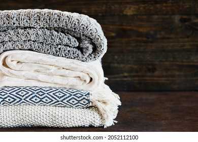 Stack Of A Soft Knit Throw Blankets Against A Rustic Background With Selective Focus And Blurred Background. Room For Copy Space.