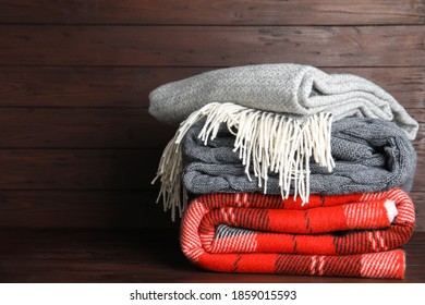 Stack of soft plaids on brown wooden table, space for text