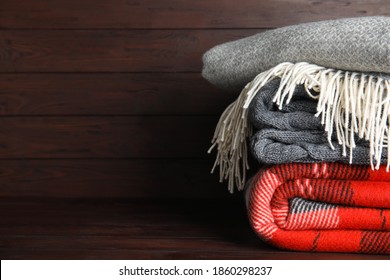 Stack of soft plaids on brown wooden table, closeup. Space for text