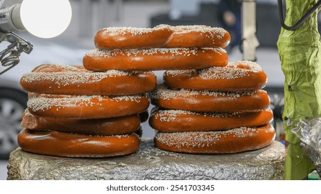 A stack of soft pretzels, sprinkled with salt, sit on a counter.