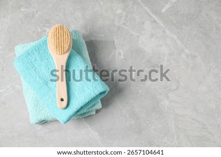 Stack of soft towels and brush on grey marble table, top view. Space for text