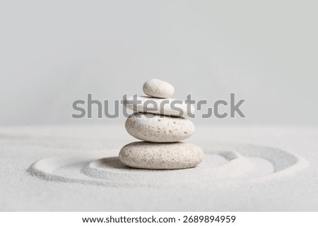 Stack of spa stones on light sand against grey wall. Zen concept