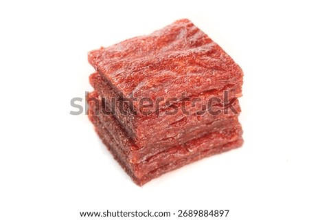 Stack of spicy red chili beef jerky strips isolated on white background, dried meat snack food with rich texture and seasoning