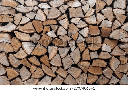 Stack of split firewood logs arranged for storage. Natural wooden texture, rustic background. Concept of renewable fuel, winter preparation, sustainable resources, biomass energy, and traditional firewood storage.