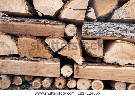 Stack of split firewood logs arranged for storage. Natural wooden texture, rustic background. Concept of renewable fuel, winter preparation, sustainable resources, biomass energy, and traditional firewood storage.