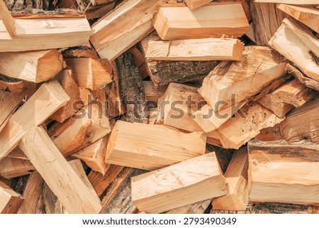 Stack of split firewood prepared for winter heating. Renewable energy source, sustainable fuel and countryside lifestyle theme. Selective focus.