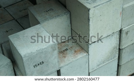 A stack of square concrete test cube blocks marked with 15x15 measurements for construction.