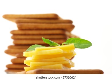 Stack Of Square Crackers With Slices Of Cheese And Basil Against White Background.